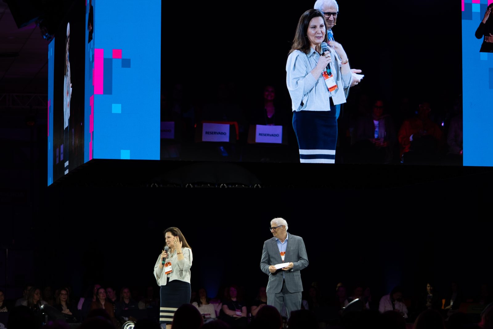 Rosimeri Dalagnol Severo e Pedro Fagherazzi no palco principal, com a imagem dos dois no telão