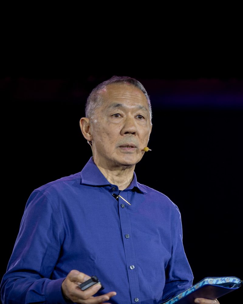 Ed Soo Hoo durante a palestra, com o passador de slides na mão