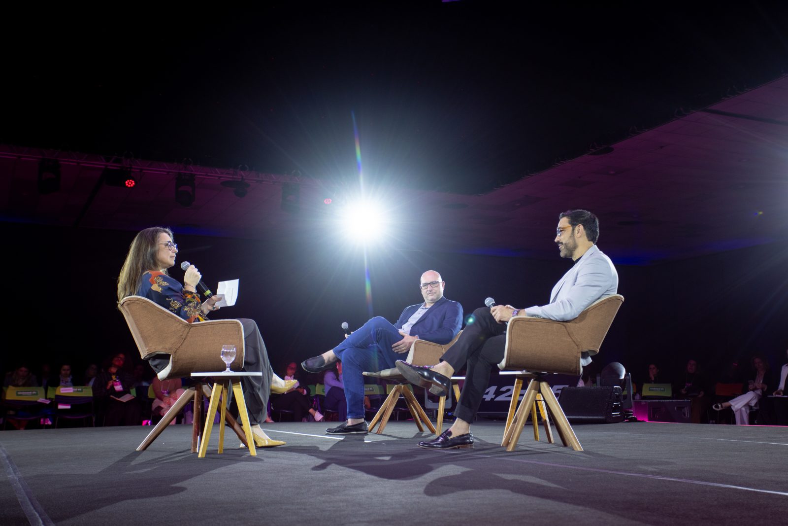 Sabrina Thomazi, Giuliano Fornazier e Leandro Firme conversam em poltronas no palco principal
