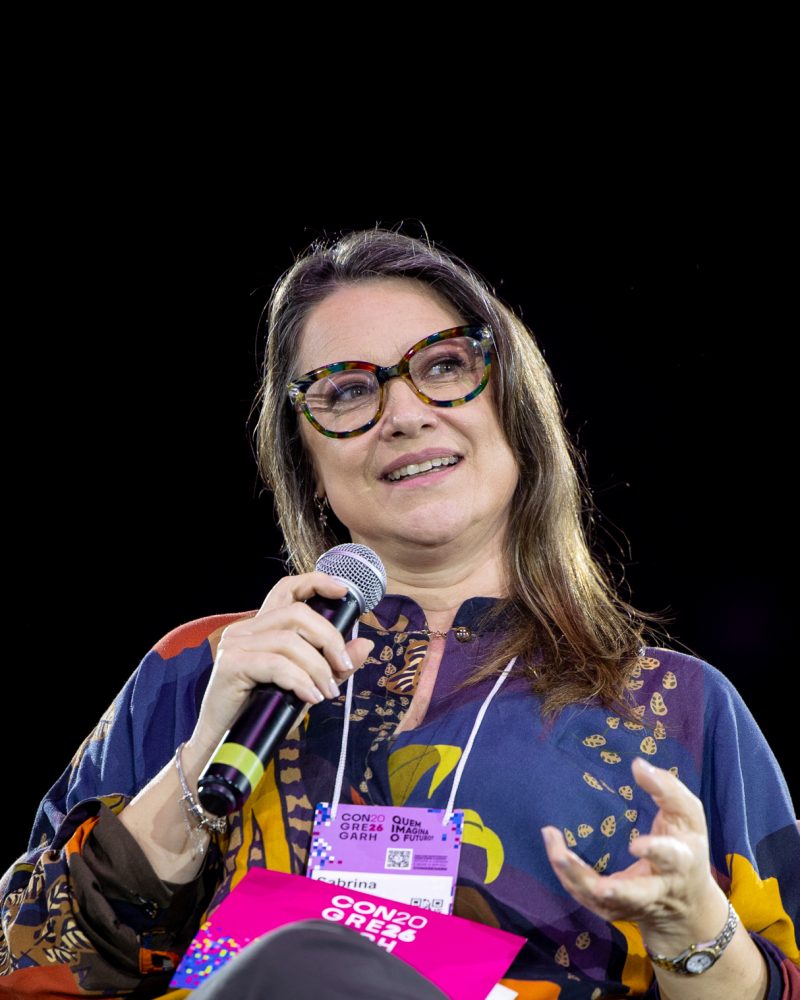 Sabrina Thomazi fala ao microfone na mediação do painel
