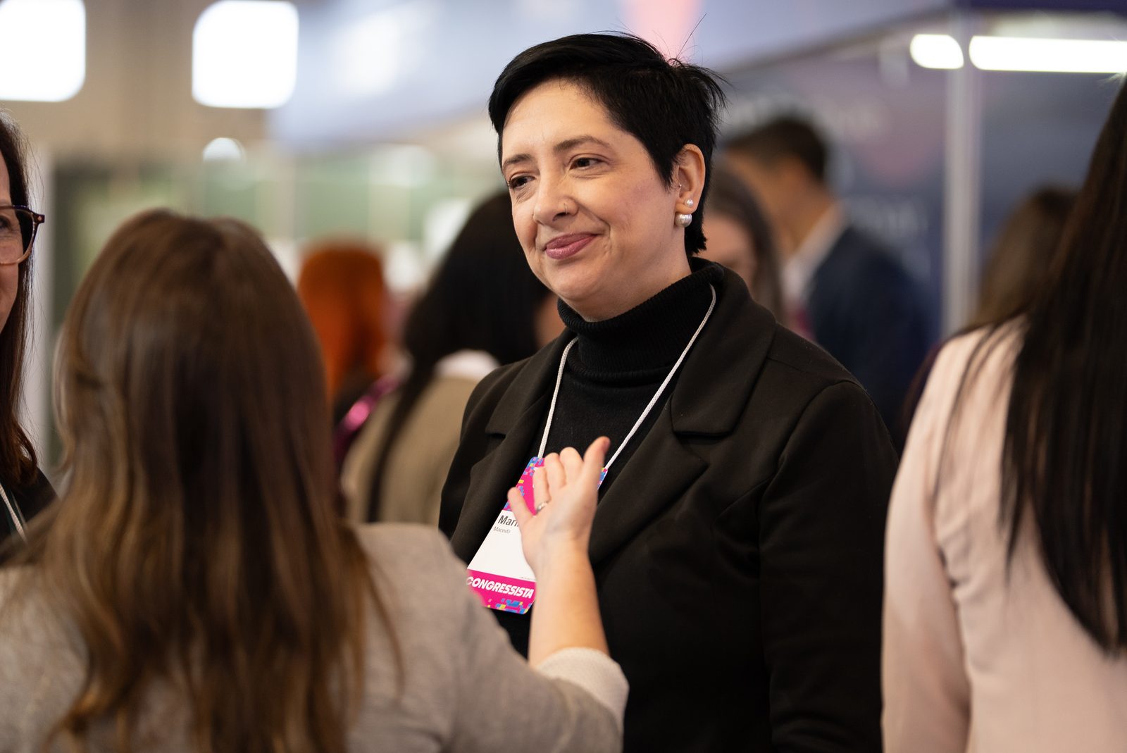 Participante sorri em conversa nos corredores do evento