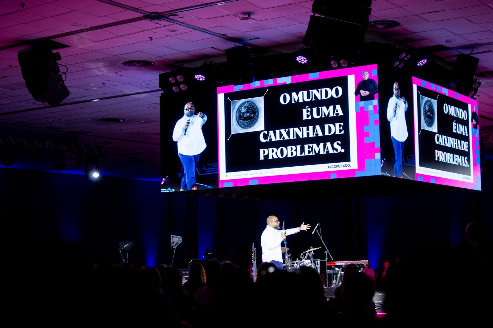 Michel Alcoforado no palco principal e no telão, ao lado do slide O mundo é uma caixinha de problemas