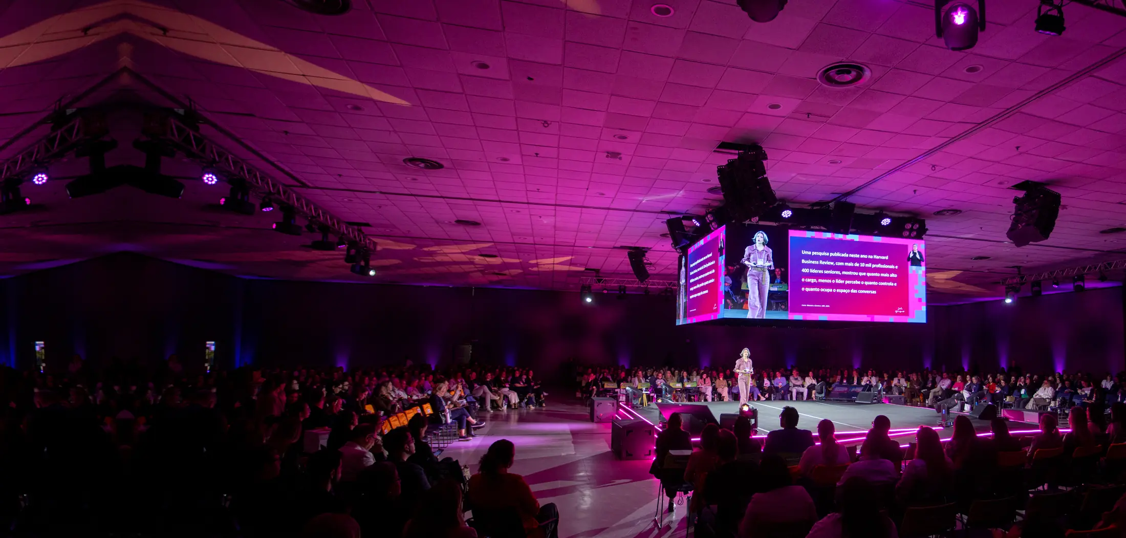 Palco central do CONGREGARH 2026 com o telão aceso acima dele e o auditório sob luz rosa